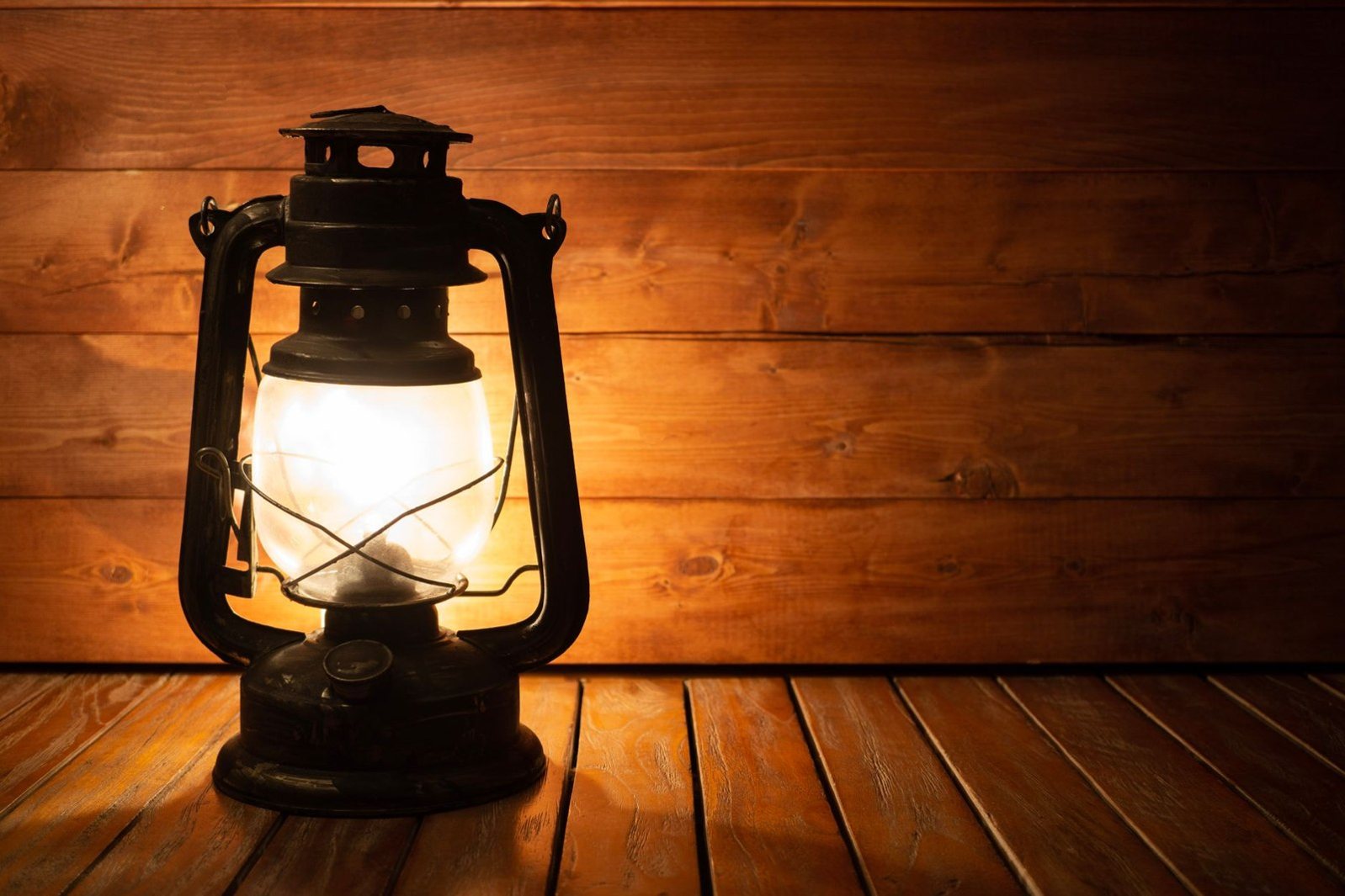 A rustic vintage lantern casting a warm glow on a wooden wall, ideal for cozy settings.
